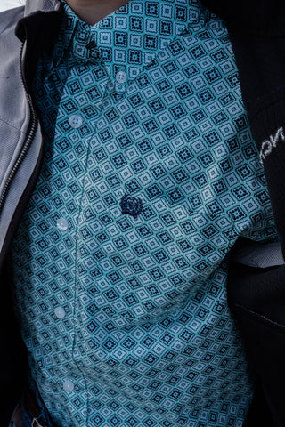 Close-up of a blue patterned shirt with a backpack in the background