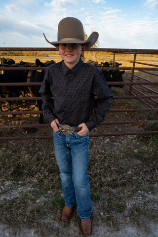 Person wearing a cowboy hat and standing in front of a pen with cattle