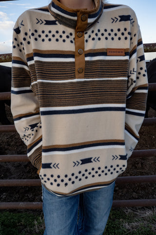 Person wearing a patterned sweater with stripes and buttons, standing outdoors.