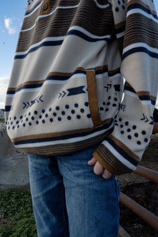 Person wearing a patterned sweater with blue jeans outdoors