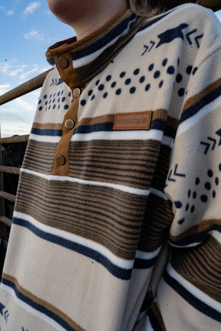 Close-up of a person wearing a patterned sweater with buttons against a blue sky.