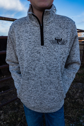 Person wearing a gray pullover with a logo in an outdoor setting