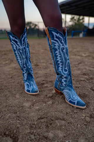 Blue embroidered cowboy boots on a dirt ground with a blurred background