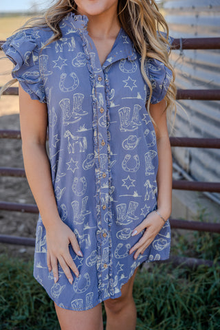 Woman wearing a blue dress with cowboy print in an outdoor setting