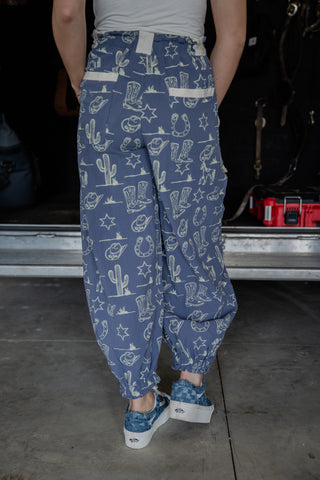 Person wearing blue patterned pants with a white top in a garage setting
