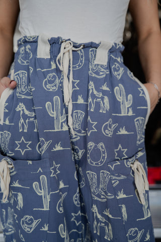 Blue patterned pants with white graphics worn by a person, blurred background