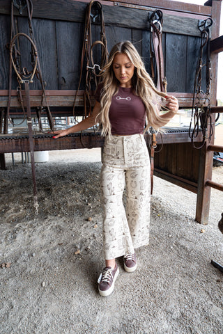 Woman standing in a stable with horse equipment in the background