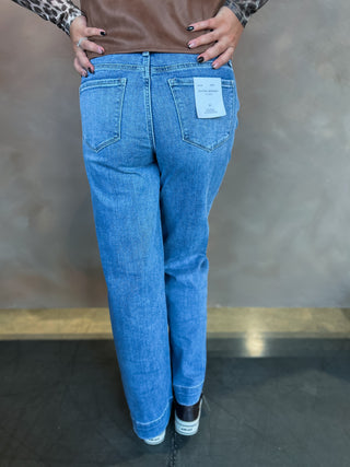 Blue jeans with a visible brand tag worn by a person against a neutral background