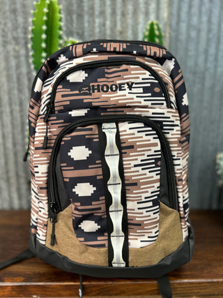Backpack with geometric pattern and 'Chooey' branding on a wooden surface.