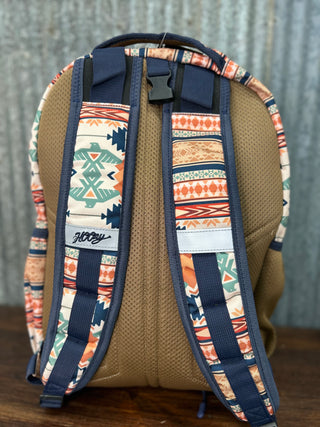 Backpack with patterned straps and back panel on a wooden surface.