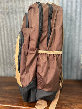Brown and beige backpack on a wooden surface with a rustic metal background