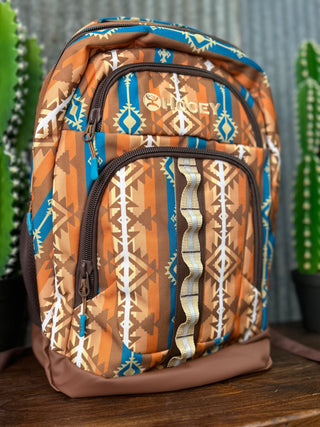Backpack with tribal pattern on a wooden surface with plants in the background