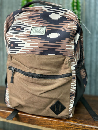 Camouflage-patterned backpack with a visible brand label on a wooden surface.