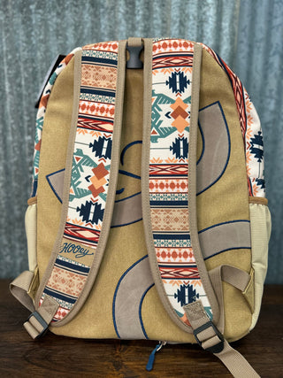 Backpack with patterned straps on a wooden surface and gray background