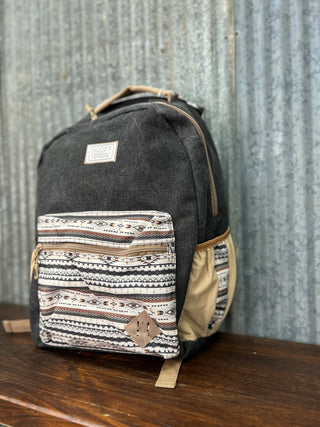 Backpack with patterned pocket on a wooden surface against a corrugated metal background