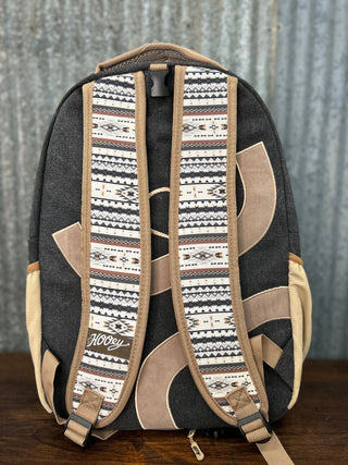 Backpack with patterned straps on a wooden surface and metal wall background