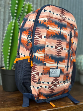Backpack with geometric pattern on a wooden surface with a cactus in the background