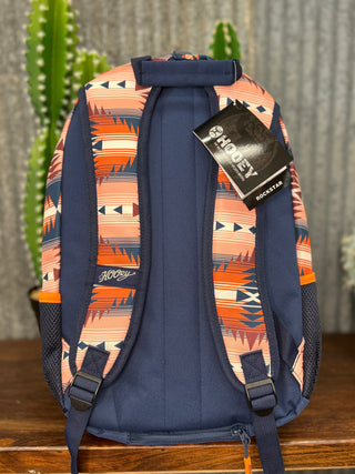 Backpack with a patterned design and visible brand tag on a wooden surface.
