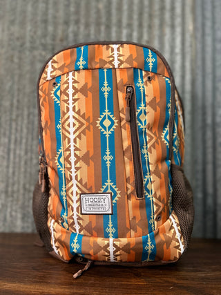 Backpack with tribal pattern on a wooden surface and metal wall background