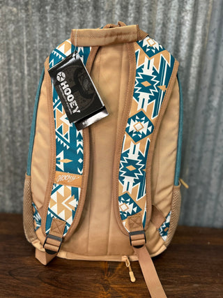 Backpack with geometric pattern and visible brand tag on a wooden surface.