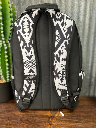 Black and white patterned backpack on a wooden surface with a cactus in the background