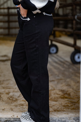 Person wearing black pants and a patterned sweater in an indoor setting