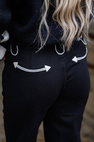 Person wearing black pants with white arrow designs on a blurred background