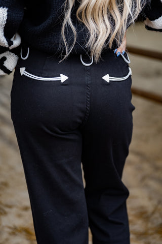 Person wearing black pants with white arrow designs on a blurred background