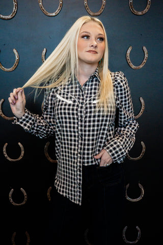 Person wearing a black and white checkered shirt with a dark background featuring horseshoe patterns.