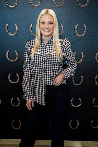 Person wearing a checkered shirt in front of a dark background with horse shoe patterns