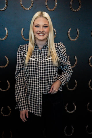 Woman wearing a checkered shirt against a dark background with horseshoe patterns