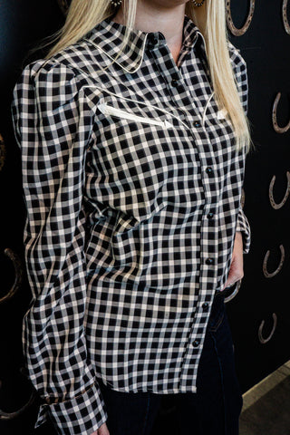 Person wearing a black and white checkered shirt with a blurred background
