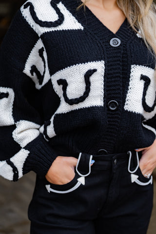 Black and white patterned cardigan worn by a person with a blurred background