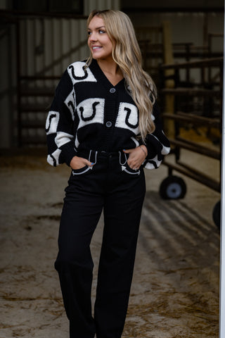 Woman wearing a black and white patterned cardigan in an indoor setting