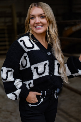 Woman wearing a black and white patterned cardigan with a blurred background