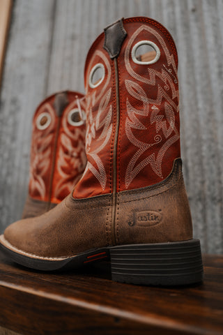Brown cowboy boots with intricate designs on a wooden surface and rustic background