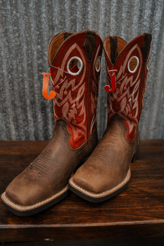 Pair of brown cowboy boots with red and white designs on a wooden surface.