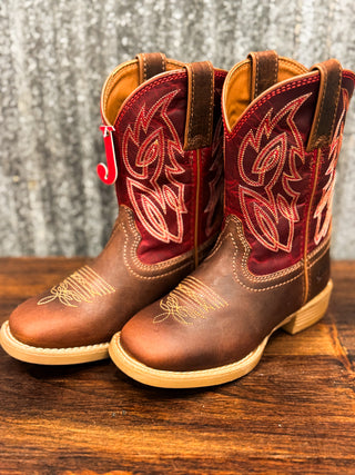 Pair of brown and red cowboy boots on a wooden surface with a rustic background.