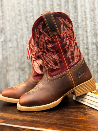 Brown cowboy boots with red stitching on a wooden surface