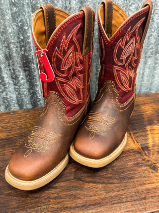 Pair of brown and red cowboy boots on a wooden surface with a gray textured background.