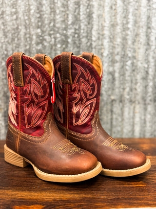 Pair of brown and red cowboy boots on a wooden surface with a metallic background