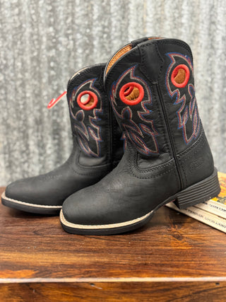 Pair of black cowboy boots with red accents on a wooden surface.