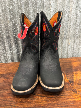 Pair of black cowboy boots with red accents on a wooden surface.