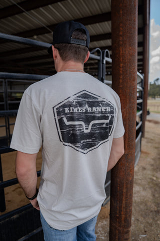 Man wearing a gray t-shirt with 'Kings Ranch' logo in a barn setting