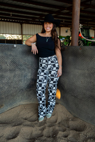 Woman in a black top and checkered pants standing in a stable.