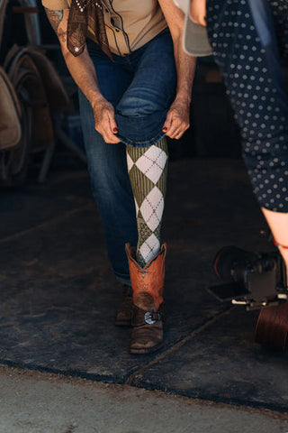 Person wearing a patterned sock and cowboy boot in an indoor setting