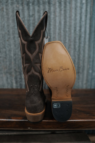 Brown cowboy boot with visible brand name on a wooden surface and metal background