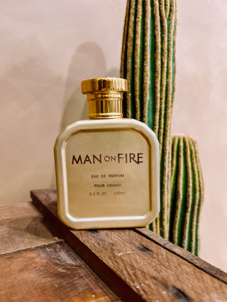 Perfume bottle labeled 'Man on Fire' on a wooden surface with a cactus in the background
