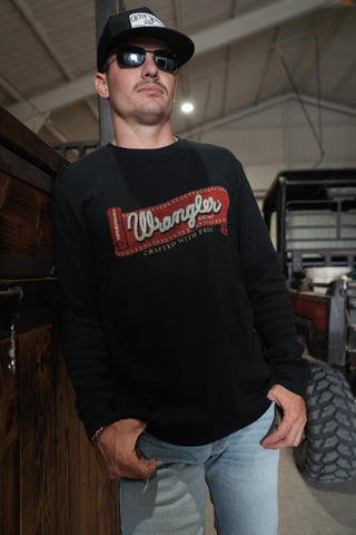 Man wearing a black Wrangler sweatshirt in an indoor setting with vehicles in the background