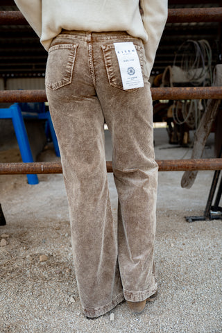 Brown corduroy pants with a tag on a person standing next to a metal railing.